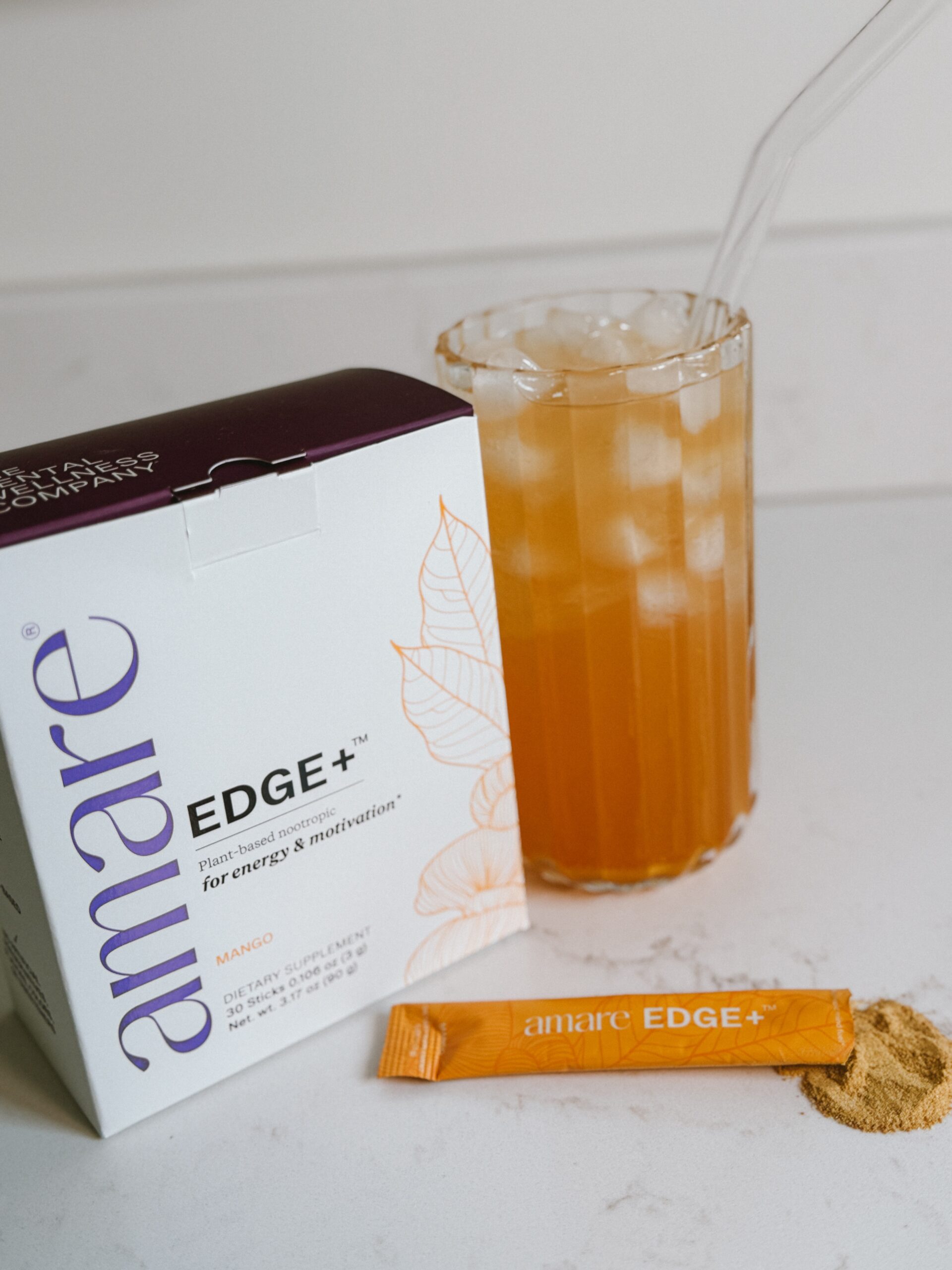 Amare Edge+ Mango box beside a glass of Happy Juice over ice