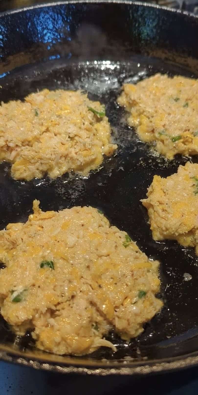 Cheesy chicken fritters sizzling golden in a cast iron skillet