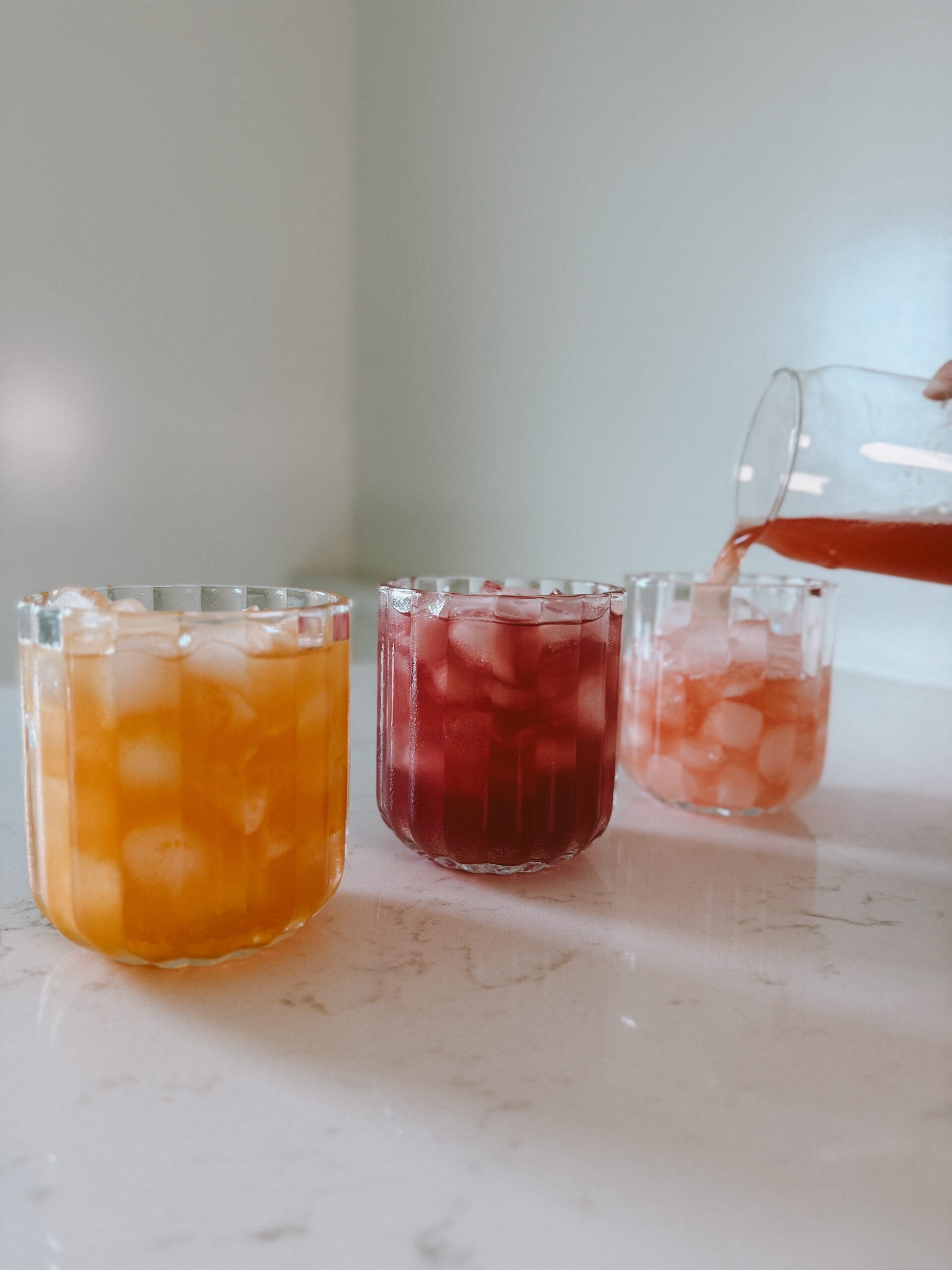 Three glasses of Happy Juice over ice in different flavors